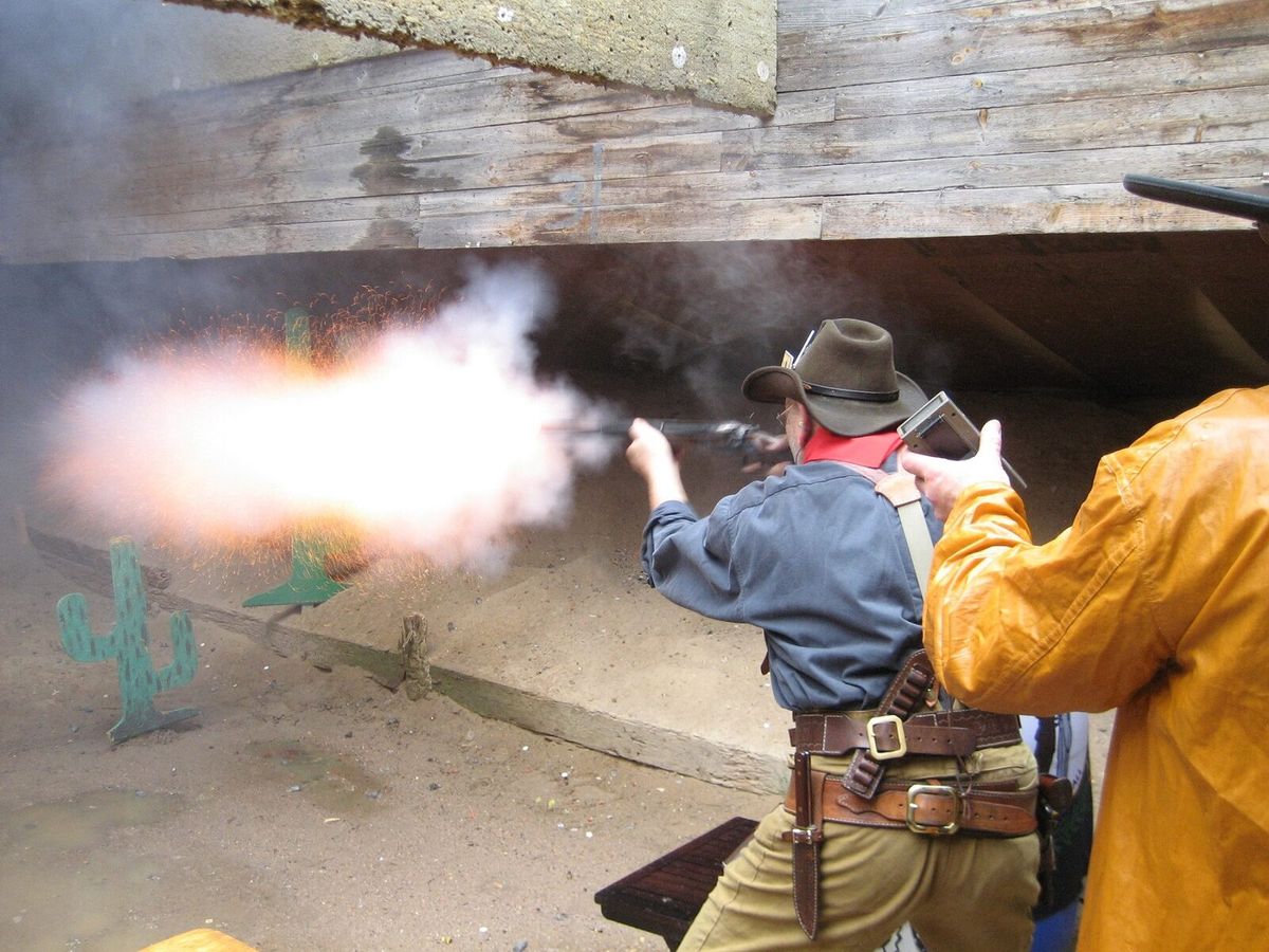 Schütze beim Cowboy Action Shooting in Westernkleidung, daneben ein Standaufsichtführender