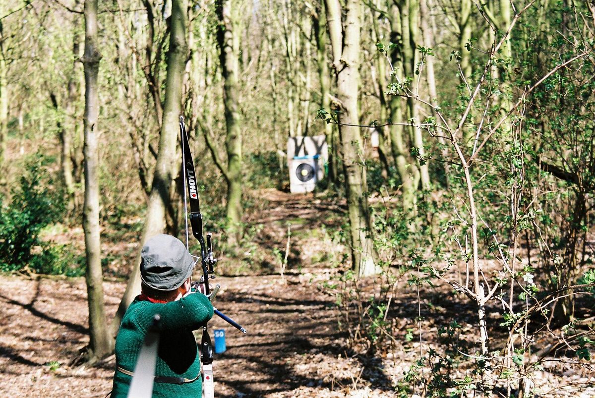 Recurve-Feldbogenschütze zielt im bewaldeten Parcours auf eine Scheibe