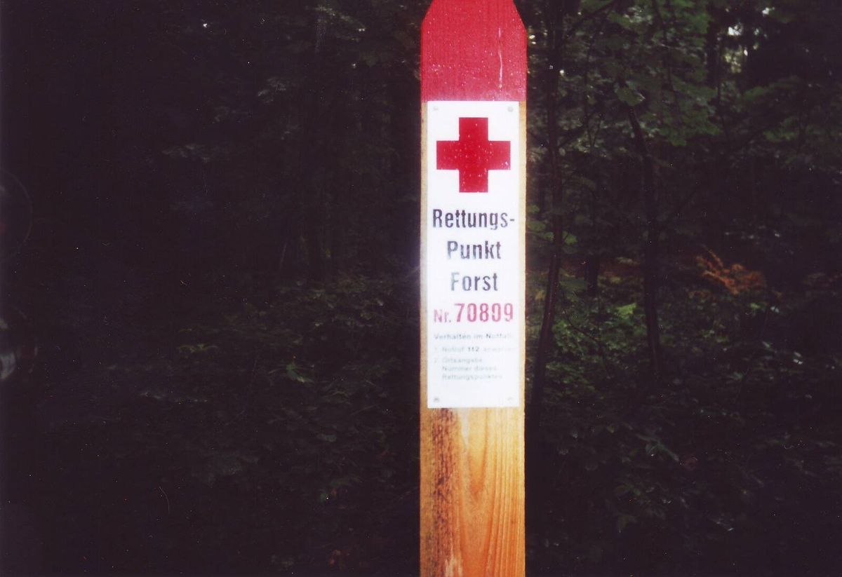 Schild eines forstlichen Rettungspunkts am Waldrand