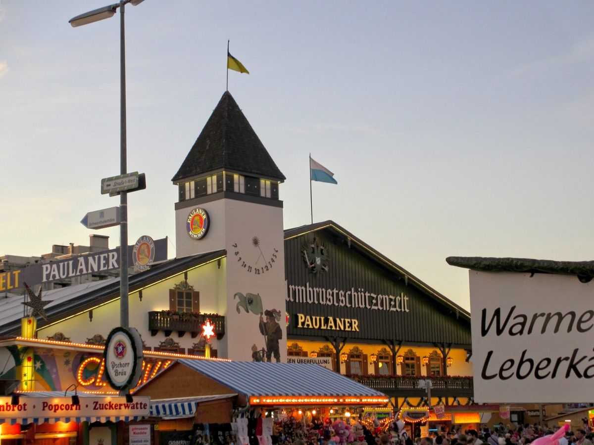 Armbrustschützenzelt auf der Wiesn bei Abenddämmerung, daneben ein Wegweiser zur U-Bahn Schwanthalerhöhe