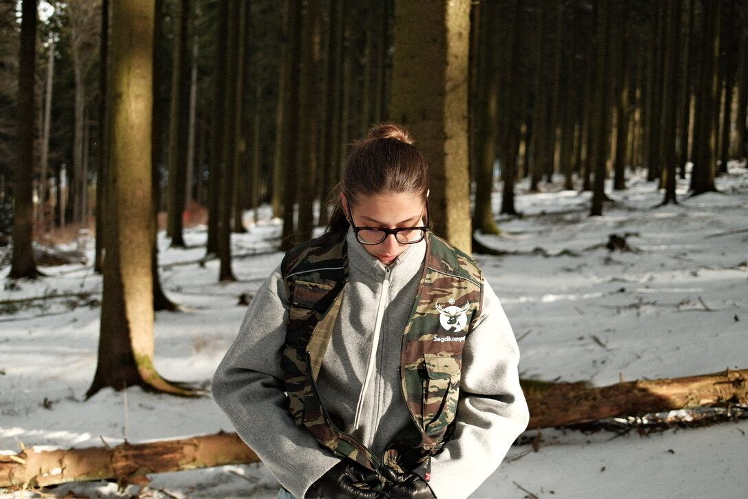 Lorena de Marco im winterlichen Wald mit Jagdkompass-Weste