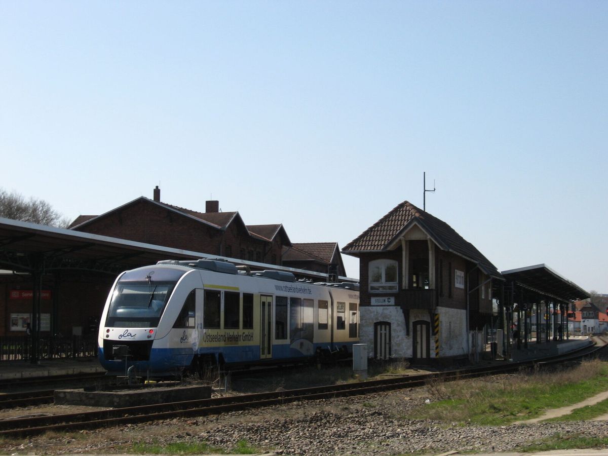 Regionaltriebwagen am Bahnsteig in Parchim neben einem alten Stellwerksgebäude