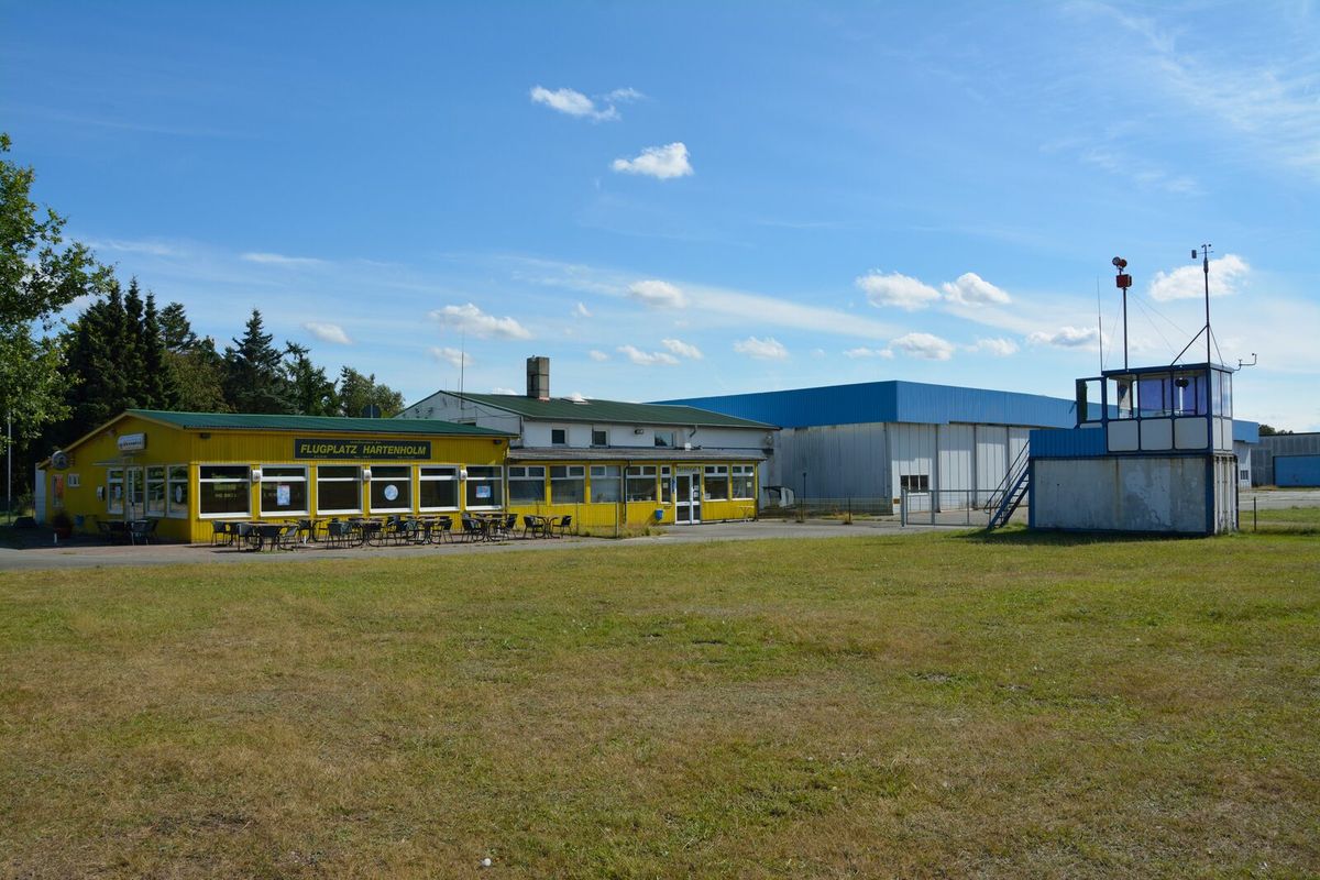 Terminalgebäude und Tower des Flugplatzes Hartenholm bei Hasenmoor unter blauem Himmel