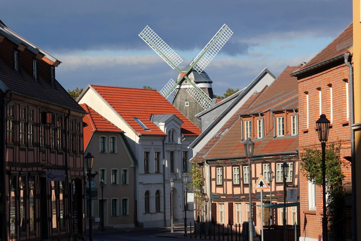 Altstadtstraße in Röbel an der Müritz mit Fachwerkhäusern und einer Holländerwindmühle im Hintergrund