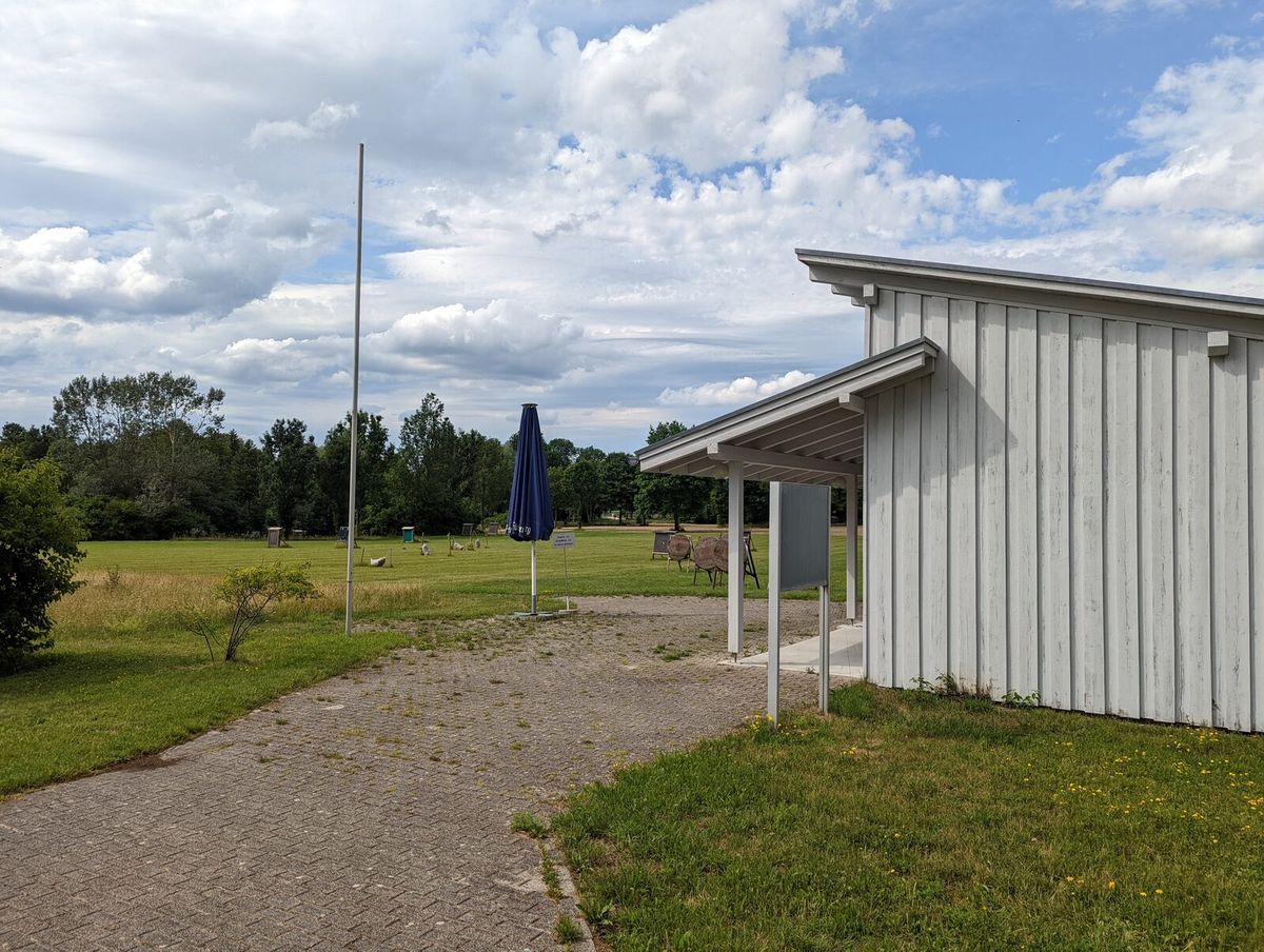 Bogenplatz im Freien mit Zielscheiben auf einer Rasenfläche und Absperrung