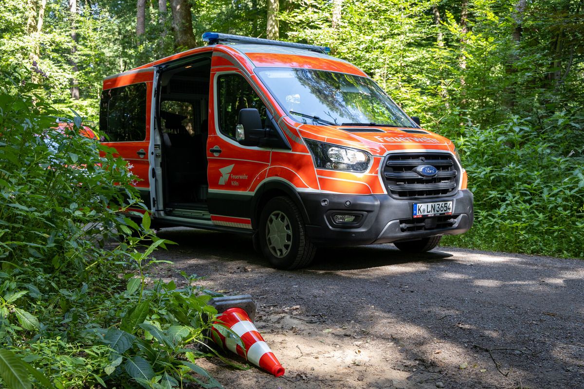 Feuerwehrfahrzeug auf einem schmalen Waldweg mit Leitkegel